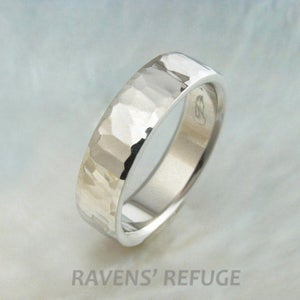 May include: A silver hammered wedding band with a smooth interior. The band is made of metal and has a textured finish.