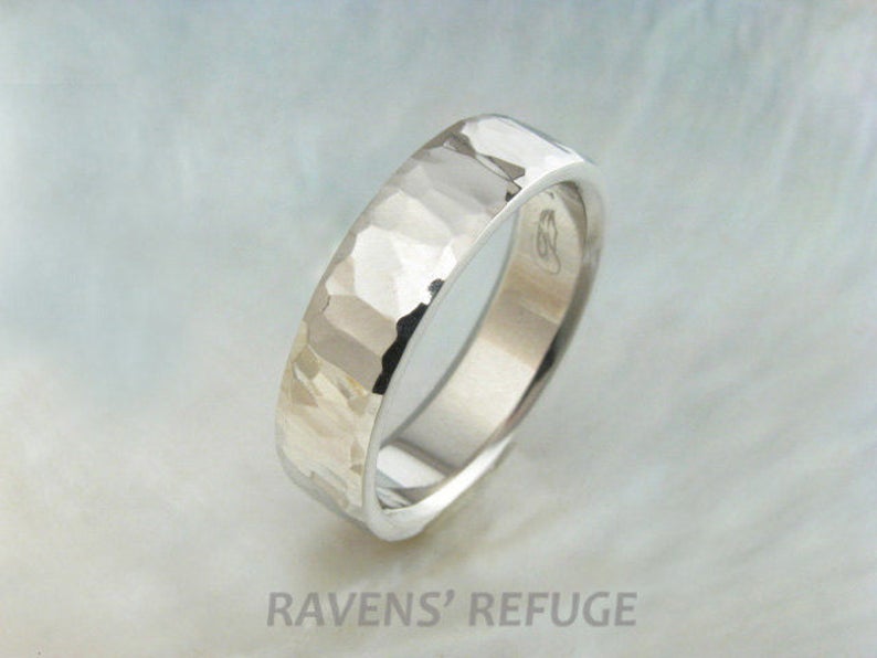 May include: A silver hammered wedding band with a smooth interior. The band is made of metal and has a textured finish.