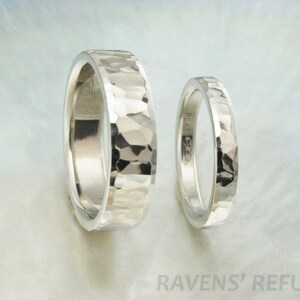 May include: Two silver hammered wedding bands. The bands are both smooth and have a hammered texture. The bands are both about the same width.