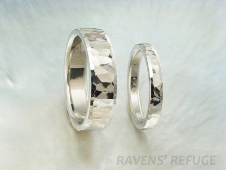 May include: Two silver hammered wedding bands. The bands are both smooth and have a hammered texture. The bands are both about the same width.