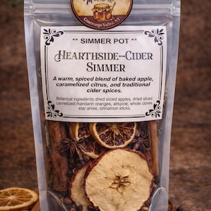 May include: A clear bag filled with dried apple slices, cinnamon sticks, star anise, and whole cloves. The label reads "Hearthside-Cider Simmer" with a description of the ingredients. A round sticker at the top reads "Valley Hearth & Hive".