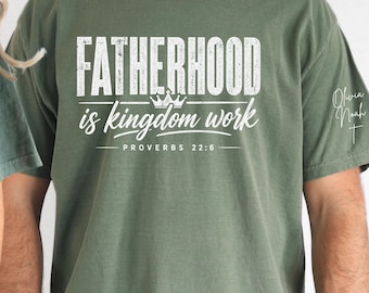Puede incluir: Camiseta verde oliva con el texto blanco "FATHERHOOD is kingdom work", con un gráfico de corona. El texto "PROVERBIOS 22:6" está debajo. La manga tiene la firma "Olivia Noah".