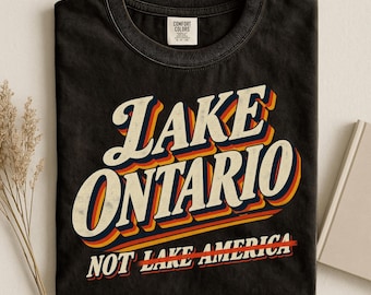 Statement T-shirt over het Ontariomeer in een opvallende, handgeschreven letterstijl. Comfort Colors® T-shirt met retro graphic print, anti-Trump T-shirt.