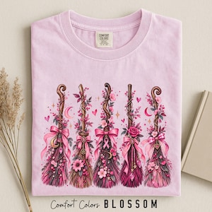 ピンクの魔女のほうき柄コンフォートカラーズ®シャツ、コケットハロウィンTシャツ、花柄魔女Tシャツ。ピンクのリボン付きコテージコア魔女風