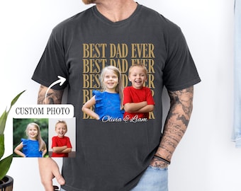 Puede incluir: Camiseta gris oscuro con el texto "BEST DAD EVER" en un patrón repetido. La camiseta presenta una foto personalizada de dos niños, una niña de azul y un niño de rojo, con los nombres "Olivia & Liam" debajo.