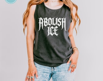 Puede incluir: Una camiseta sin mangas de color gris carbón con el texto blanco ABOLISH ICE en una fuente gótica estilizada centrada en el pecho. La prenda se combina con unos vaqueros de mezclilla azul claro con efecto lavado al ácido, estilo casual.