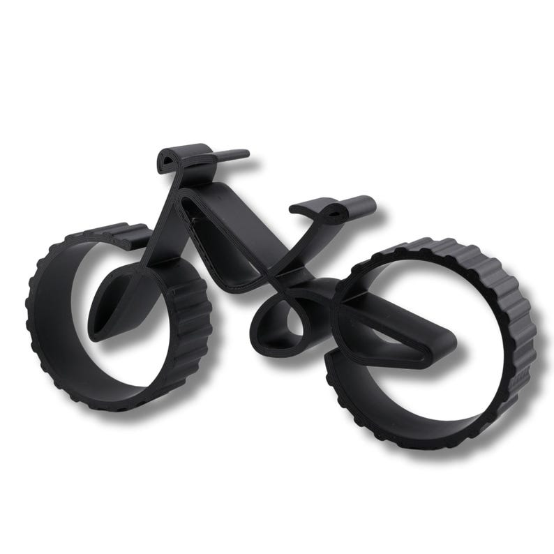 Geometric bicycle sculpture with hollow frame and thick ridged wheels, viewed from a low angle front right on a white background. Visible layering texture along edges and smooth curved surfaces.