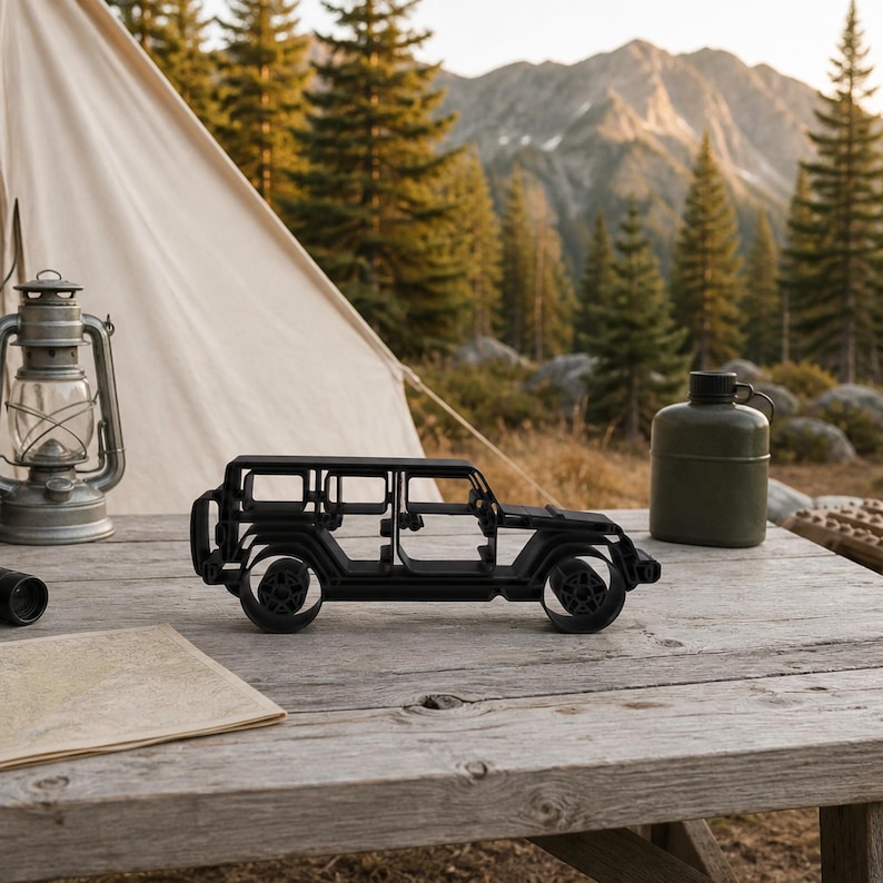 Black freestanding Jeep Wrangler 4 Door Side View line-art sculpture displayed outdoors in a alpine forest overland basecamp at a mountain trailhead.