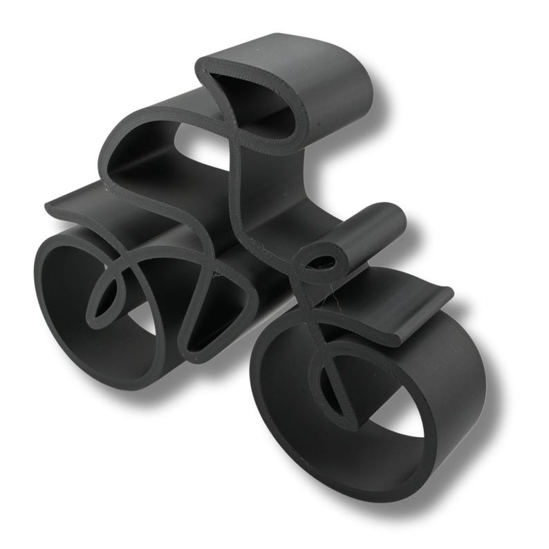 Minimalist cyclist sculpture in a continuous line style, manufactured from plastic and viewed from a slightly elevated angle to highlight its dimensional curves and artistic form.