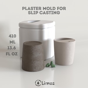May include: A white plaster mold for slip casting, with the text "PLASTER MOLD FOR SLIP CASTING". The image shows a white container, a brown cup, and a beige cup. The brown cup is labeled with 13.6 fl oz. Also included are small green objects.