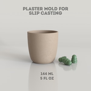Op de afbeelding: Een beige gipsen mal voor gietklei, met de tekst "PLASTER MOLD FOR SLIP CASTING". De mal heeft de vorm van een cilindrische beker, met twee groene plastic onderdelen. De beker bevat 144 ml, of 5 fl oz.
