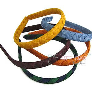May include: A collection of colorful headbands with a woven design. The headbands are in various colors, including yellow, blue, orange, green, and burgundy. The headbands are made of a smooth material and are suitable for various hairstyles.