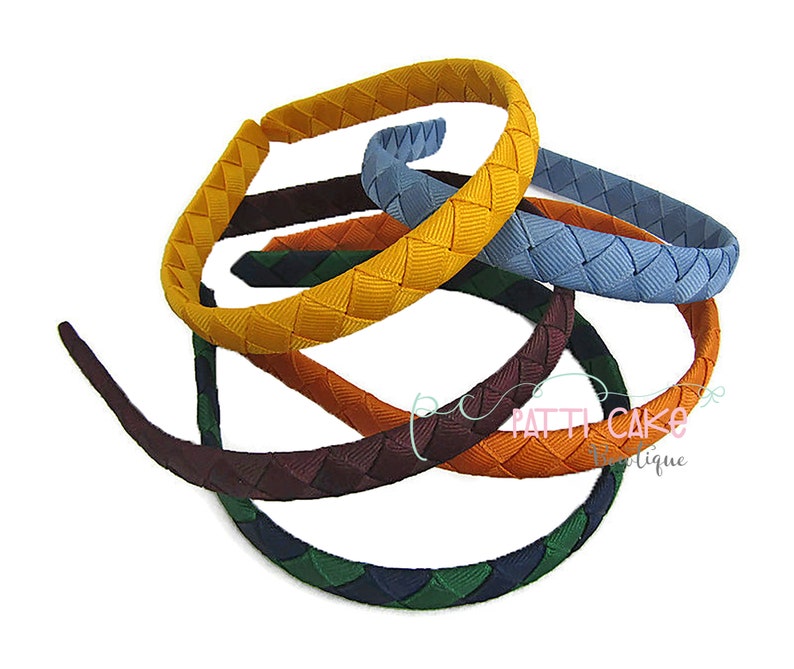 May include: A collection of colorful headbands with a woven design. The headbands are in various colors, including yellow, blue, orange, green, and burgundy. The headbands are made of a smooth material and are suitable for various hairstyles.