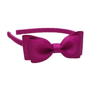 Puede incluir: Una diadema magenta con un lazo grande. El lazo est&aacute; centrado y hecho de tela acanalada. La diadema es de color magenta a juego, con un dise&ntilde;o simple y redondeado.