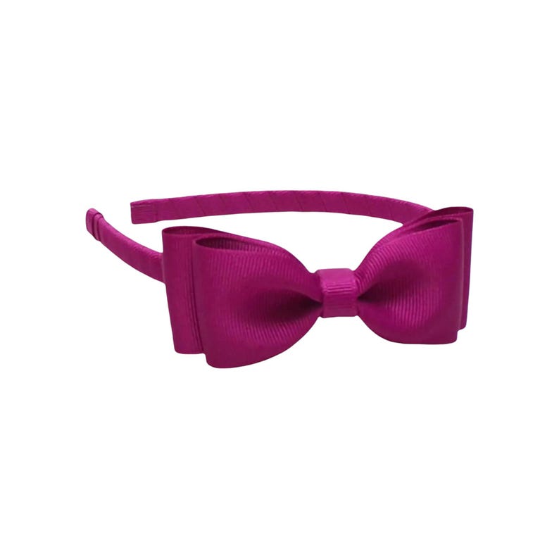 May include: A magenta-colored headband with a large bow. The bow is made of a ribbed fabric and is centered on the headband. The headband is a solid magenta color and is designed to be worn on the head.