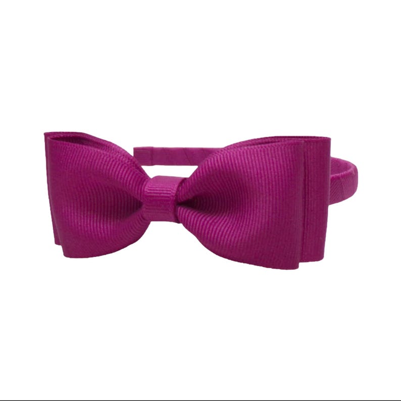 Puede incluir: Una diadema magenta con un lazo grande. El lazo est&aacute; hecho de una tela acanalada y est&aacute; centrado en la diadema. La diadema es de color s&oacute;lido y est&aacute; dise&ntilde;ada para ser usada en la cabeza.