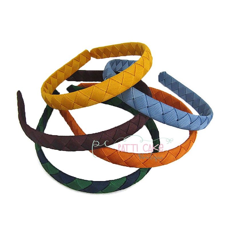 May include: A collection of colorful headbands with a woven ribbon design. The headbands are in various colors, including yellow, blue, orange, brown, and green. The headbands are displayed on a white background.
