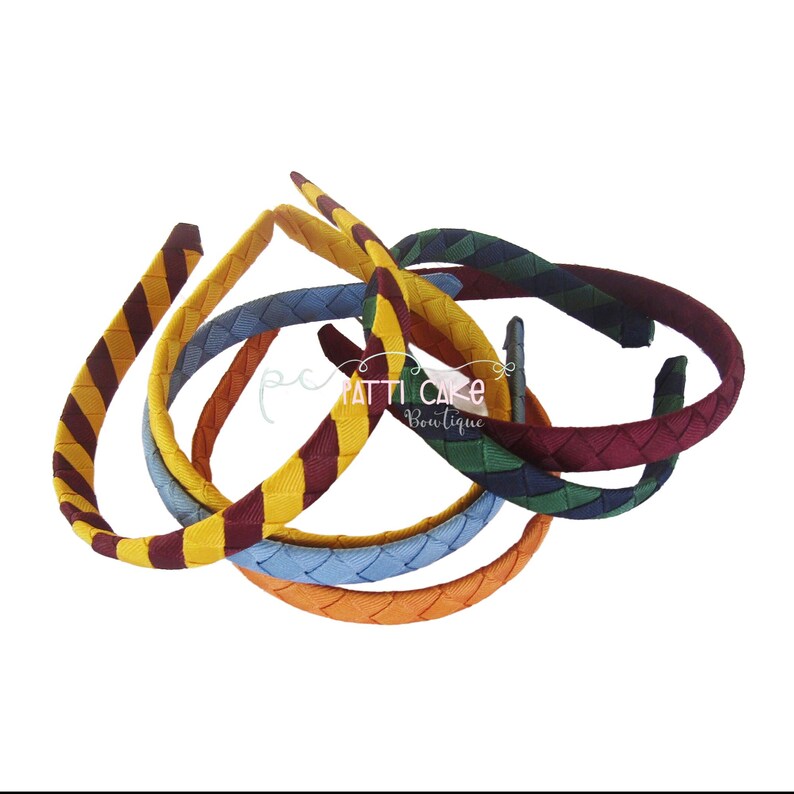 May include: A collection of braided headbands in various colors, including yellow with burgundy stripes, blue, orange, and green. The headbands are arranged in a loose pile, with the text "pc PATTI CAKE Boutique" visible.