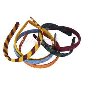May include: A collection of braided headbands in various colors, including yellow, burgundy, blue, orange, and green. The headbands are arranged in a slightly overlapping pattern, showcasing their woven texture and design.