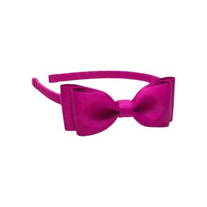 Puede incluir: Una diadema magenta con un lazo grande. El lazo est&aacute; hecho de una tela acanalada y est&aacute; centrado en la diadema. La diadema es de color liso y est&aacute; dise&ntilde;ada para ser usada en la cabeza.