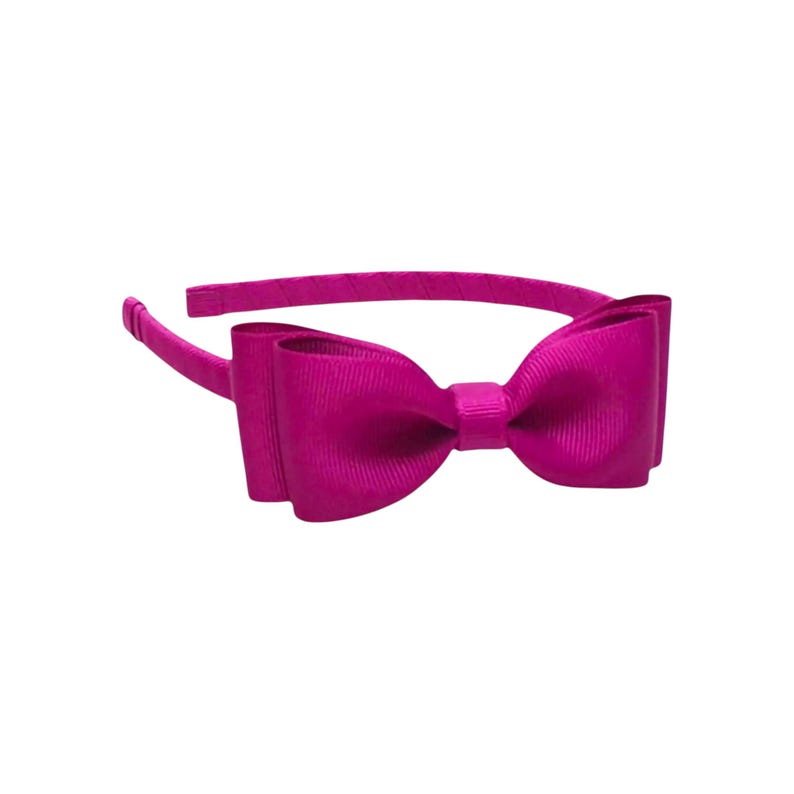 Puede incluir: Una diadema magenta con un lazo grande. El lazo est&aacute; hecho de una tela acanalada y est&aacute; centrado en la diadema. La diadema es de color liso y est&aacute; dise&ntilde;ada para ser usada en la cabeza.
