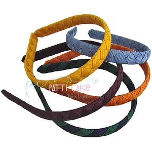 May include: A collection of colorful woven headbands in various shades, including yellow, blue, orange, and green. The headbands are arranged in a layered display, showcasing their braided texture. The image includes the text "Patti Cake Boutique".