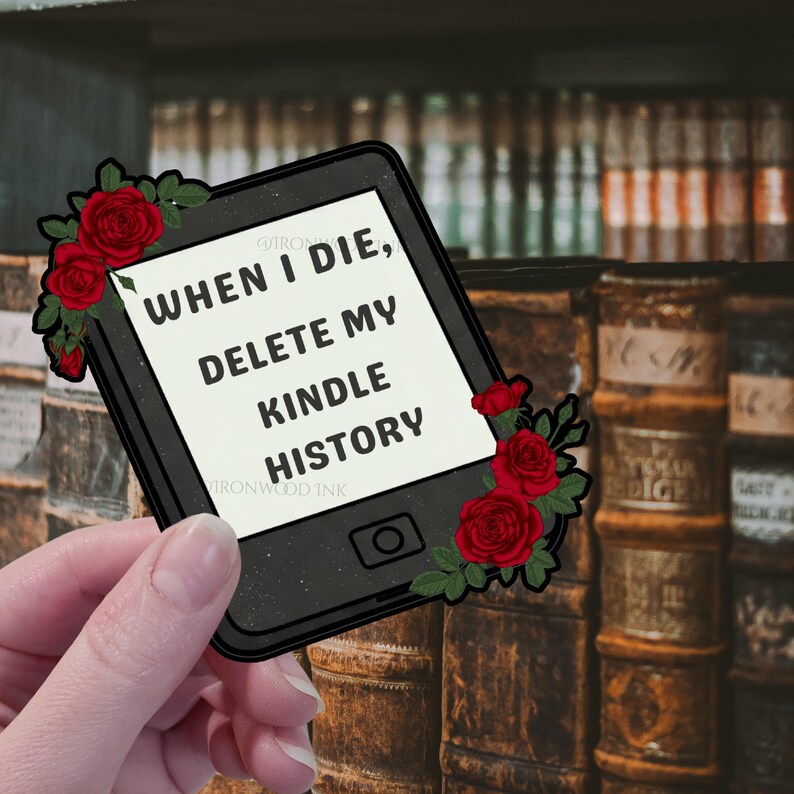 May include: A black e-reader shaped sticker featuring the text "WHEN I DIE, DELETE MY KINDLE HISTORY" in black capital letters on a white background, decorated with red roses and green leaves on the top left and bottom right corners.