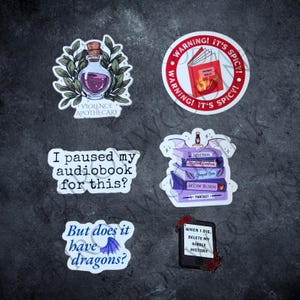 May include: A collection of six vinyl stickers featuring book-themed designs. Includes a potion bottle labeled Violence Apothecary, a red warning circle, a stack of purple books, and text-based stickers reading I paused my audiobook for this?, But does it have dragons?, and When I die, delete my kindle history.