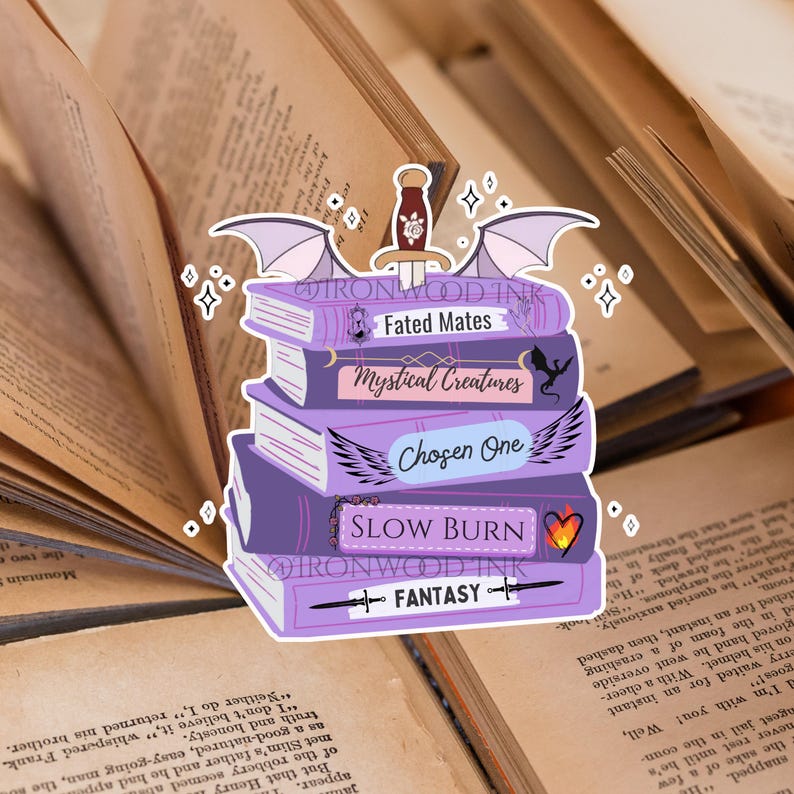 May include: A sticker featuring a stack of five purple books with a sword on top and wings on the sides. The book spines are labeled Fated Mates, Mystical Creatures, Chosen One, Slow Burn, and Fantasy, with small icons including a dragon and a heart.