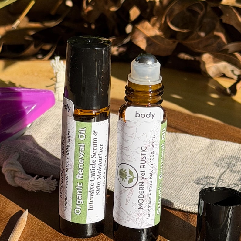 Puede incluir: Dos frascos roll-on de vidrio &aacute;mbar con tapas negras. Uno est&aacute; etiquetado como "Organic Renewal Oil" y el otro como "body". Ambos frascos tienen etiquetas blancas con detalles verdes y el texto "MODERN yet RUSTIC".