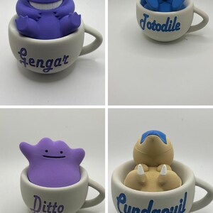 May include: Four ceramic teacups each feature a different Pok&eacute;mon character. The characters are Gengar, Totodile, Ditto, and Cyndaquil. Each character is a different color and sits inside a white teacup with the character's name.
