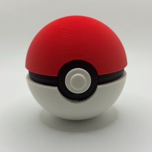 May include: A red and white Poké Ball, a spherical device used in the Pokémon franchise. The top half is red, the bottom half is white, and a black band with a white button encircles the middle. The ball is a popular item in the Pokémon universe.