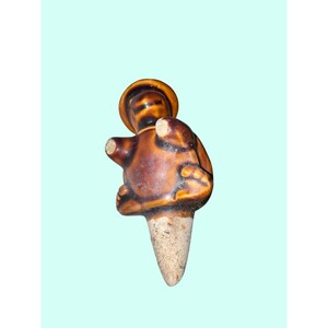 Może przedstawiać: Ceramiczny korek do butelki w kształcie figurki w kapeluszu. Figurka jest brązowa z jasną korkową podstawą. Korek ma błyszczące wykończenie i prawdopodobnie jest ręcznie robiony. Unikalny przedmiot dekoracyjny.