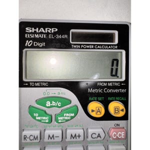 Può includere: Una calcolatrice Sharp Elsi Mate EL-344R a 10 cifre con doppia alimentazione e corpo argento e nero. Il dispositivo presenta un display digitale che mostra zero, pulsanti verdi per la conversione metrica e pulsanti gialli etichettati A e B.