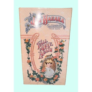 Könnte beinhalten: Vintage-Box mit pfirsichfarbenem Hintergrund, mit dem Text "HAGARA Collectibles" und "Fall in Love Again". Das Design umfasst florale Akzente und ein Porträt einer jungen Person. Die Box hat ein Warenzeichen.