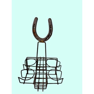 May include: A rustic metal horseshoe wine bottle and glass holder. The horseshoe is mounted above a rack designed to hold wine glasses and bottles. The metal has a weathered, aged appearance, with a dark brown color.