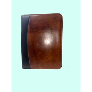 May include: A rectangular leather portfolio featuring a large, smooth brown panel on the right side and a contrasting vertical black strip along the left edge. The surface displays natural variations in color and texture across the brown leather.
