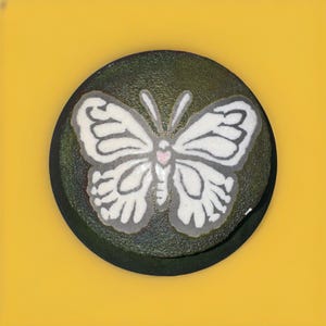 May include: A round ceramic dish with a green glaze and a white butterfly design. The butterfly has a pink heart in the centre of its body.