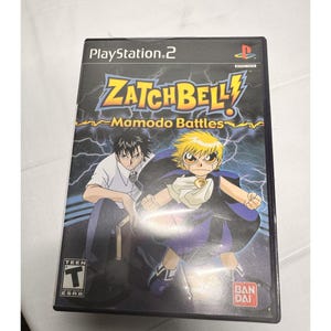 May include: Zatch Bell: Mamodo Battles PlayStation 2 game case. The cover features two anime characters, one with spiky black hair and the other with spiky blonde hair. The title is in yellow and blue with lightning bolts. The ESRB rating is Teen.