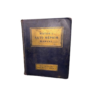 Puede incluir: Un libro antiguo de Motor's Auto Repair Manual con una cubierta azul oscuro y letras doradas. El título del libro se muestra en un recuadro dorado. La parte inferior del libro tiene el texto "KEEP 'EM ROLLING WITH MOTOR'S MANUALS."