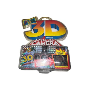May include: A vintage Spirit 3D single-use camera in its original packaging. The packaging features the words "FUN" and "3D" in bright yellow and red. The camera has a built-in flash and is smaller than actual size.