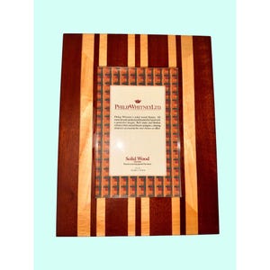 May include: A rectangular solid wood picture frame with alternating vertical stripes of light and dark brown wood. The frame has a central opening with a printed insert that reads "Philip Whitney Ltd."