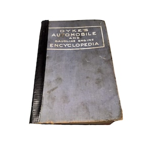 May include: A vintage book titled "Dyke's Automobile and Gasoline Engine Encyclopedia." The book has a blue cover with white lettering and a black spine. The cover shows signs of wear and age, with some discoloration and edge wear.