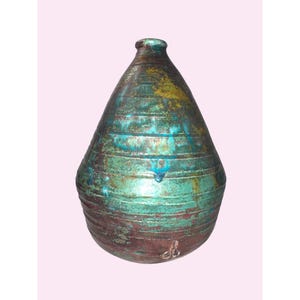 May include: A teardrop-shaped ceramic vase featuring a textured surface with horizontal ridges. The glaze displays a blend of metallic teal, deep green, and earthy brown tones with visible drip patterns and a small, light-coloured mark near the base.