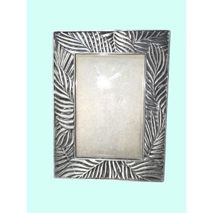 May include: A rectangular silver-colored picture frame with a palm leaf design. The frame has a detailed, textured pattern of overlapping leaves around the edges. The center is empty, ready for a photo.