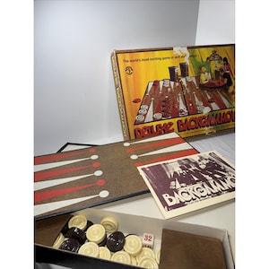 May include: Vintage Deluxe Backgammon game set. The box features a colorful illustration of a backgammon board with players. Includes a game board, dice, and playing pieces in a box. The game board is brown with red and white stripes.