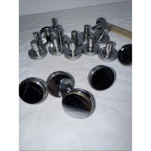 May include: A collection of circular cabinet knobs featuring a polished chrome finish with a black centre inlay. Each knob has a cylindrical base and a flat top. A wooden ruler is visible in the background, showing a measurement of 7.6 cm.
