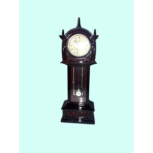 May include: A dark brown wooden grandfather clock featuring a round clock face with Roman numerals, a central finial, and decorative carved details. The lower section displays a glass panel revealing two hanging silver weights and a pendulum.