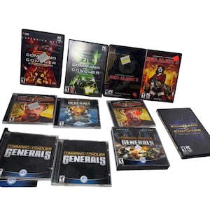May include: A collection of PC video game boxes, including titles like "Command & Conquer," "Red Alert 3," and "Generals." The games feature various cover art, with some showing characters and others featuring action scenes. The games are in their original packaging.