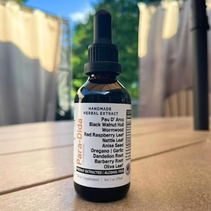May include: A brown glass bottle of herbal extract with a black dropper. The label reads "Handmade Herbal Extract" and lists ingredients like Pau D' Arco and Red Raspberry Leaf. The bottle contains 2 fl oz (59ml).